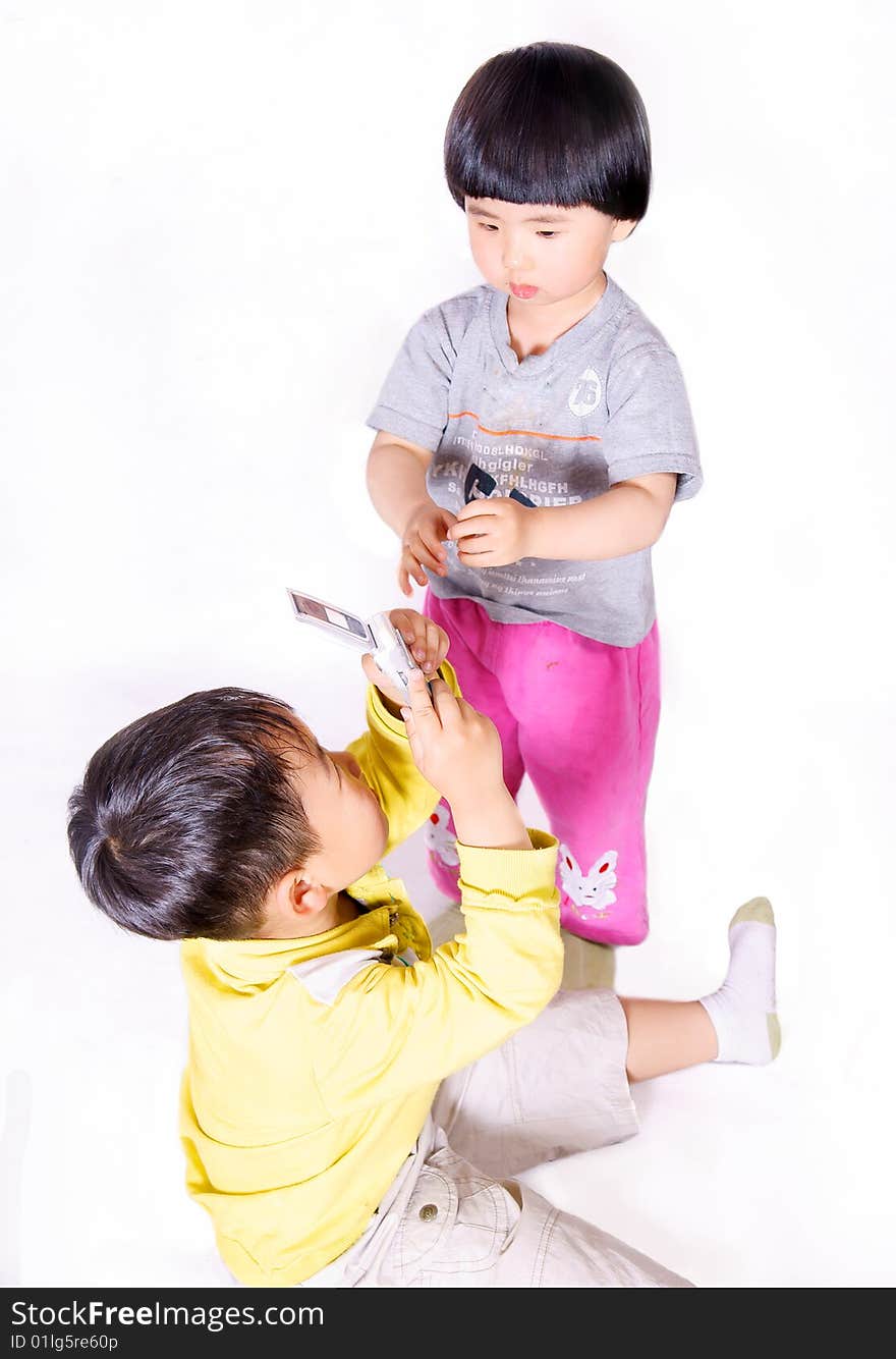 A picture of a little chinese boy taking picture of a little girl with cell phone. A picture of a little chinese boy taking picture of a little girl with cell phone