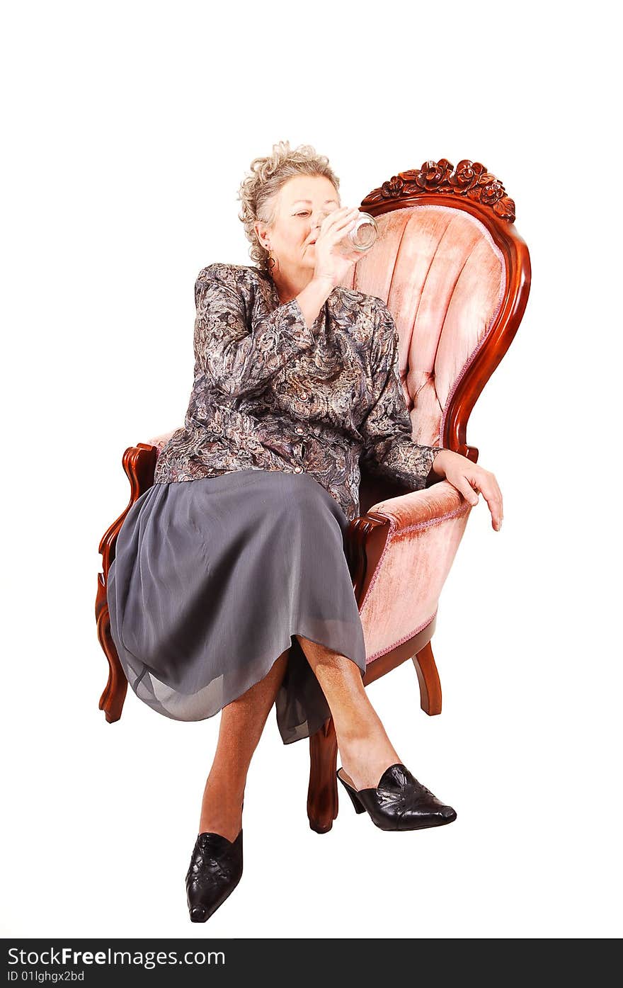 All dressed up elderly woman sitting in an pink armchair, enjoying her life
and having a glass of water, for white background. All dressed up elderly woman sitting in an pink armchair, enjoying her life
and having a glass of water, for white background..