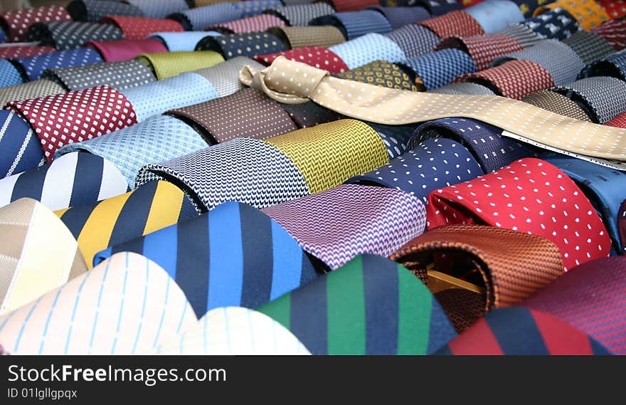 Rolled up colorful ties and one unrolled tie. Rolled up colorful ties and one unrolled tie