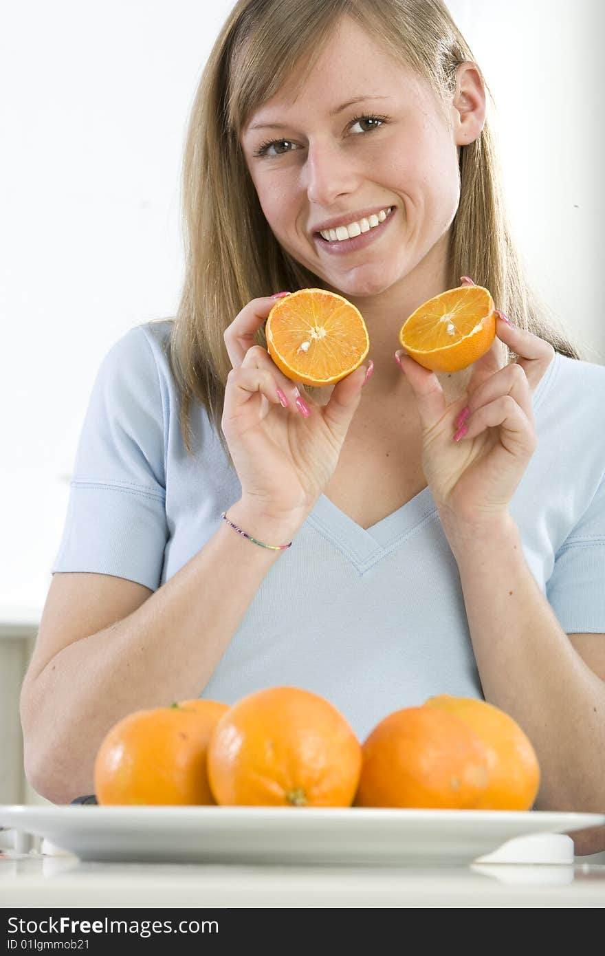 Beautiful girl in the kitchen with juicy orange