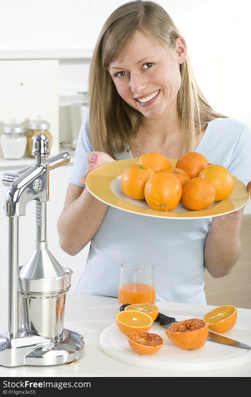 Beautiful girl in the kitchen with juicy orange