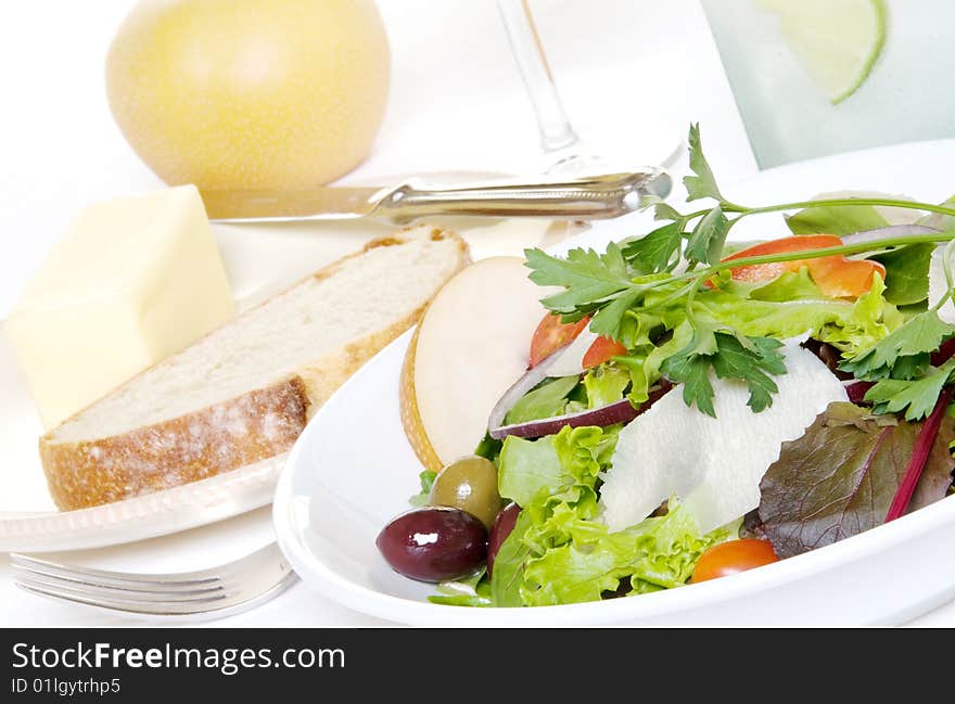 Green salad with french bread, an asian pear, wine, and glass of water. Green salad with french bread, an asian pear, wine, and glass of water