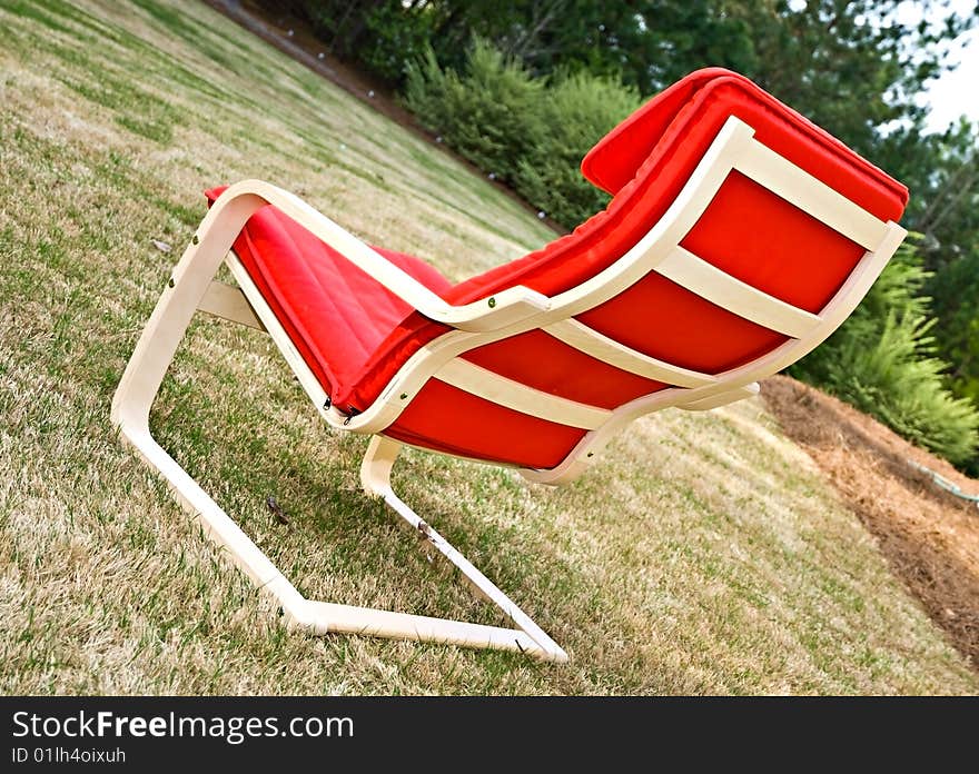 A empty, modern, red chair sitting in the grass. A empty, modern, red chair sitting in the grass.