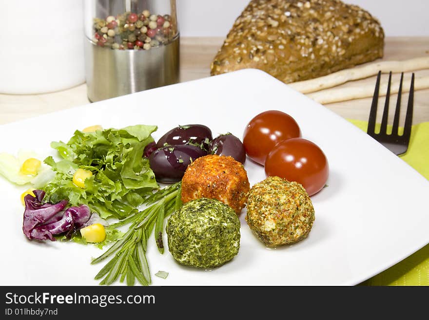 A plate with cheese, olives and tomatoes on a wooden table. A plate with cheese, olives and tomatoes on a wooden table.