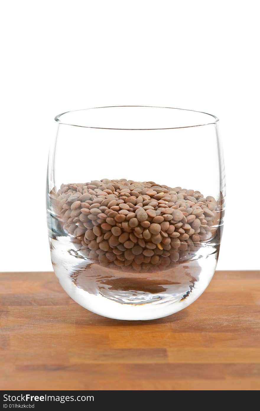 Pardina lentils in glass on wooden table, white background