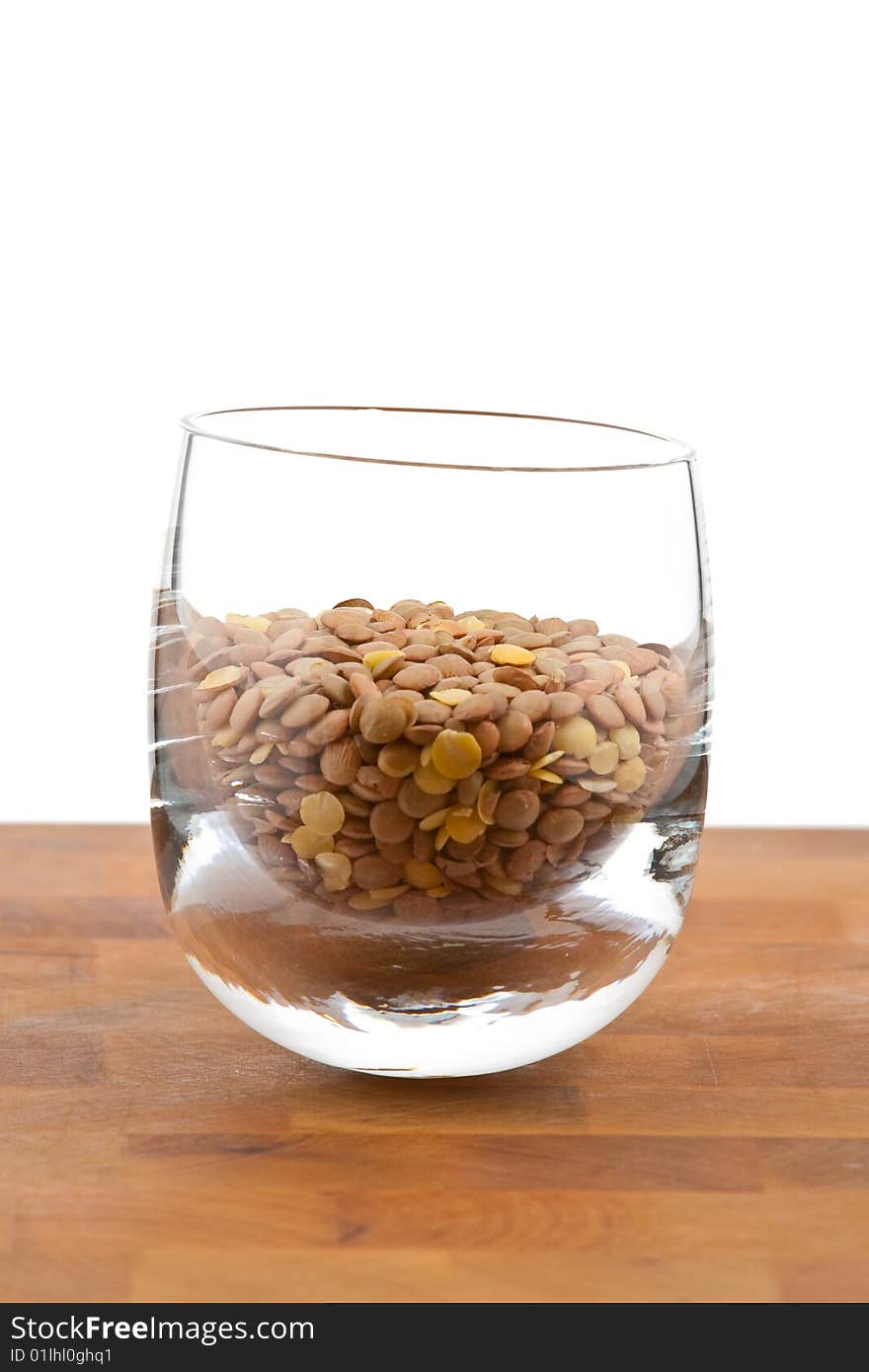 Lentils in glass on wooden table, white background