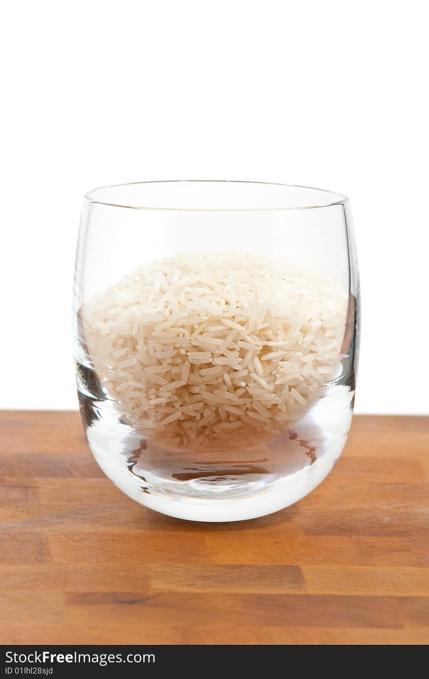 Basmati rice in glass on wooden table, white background