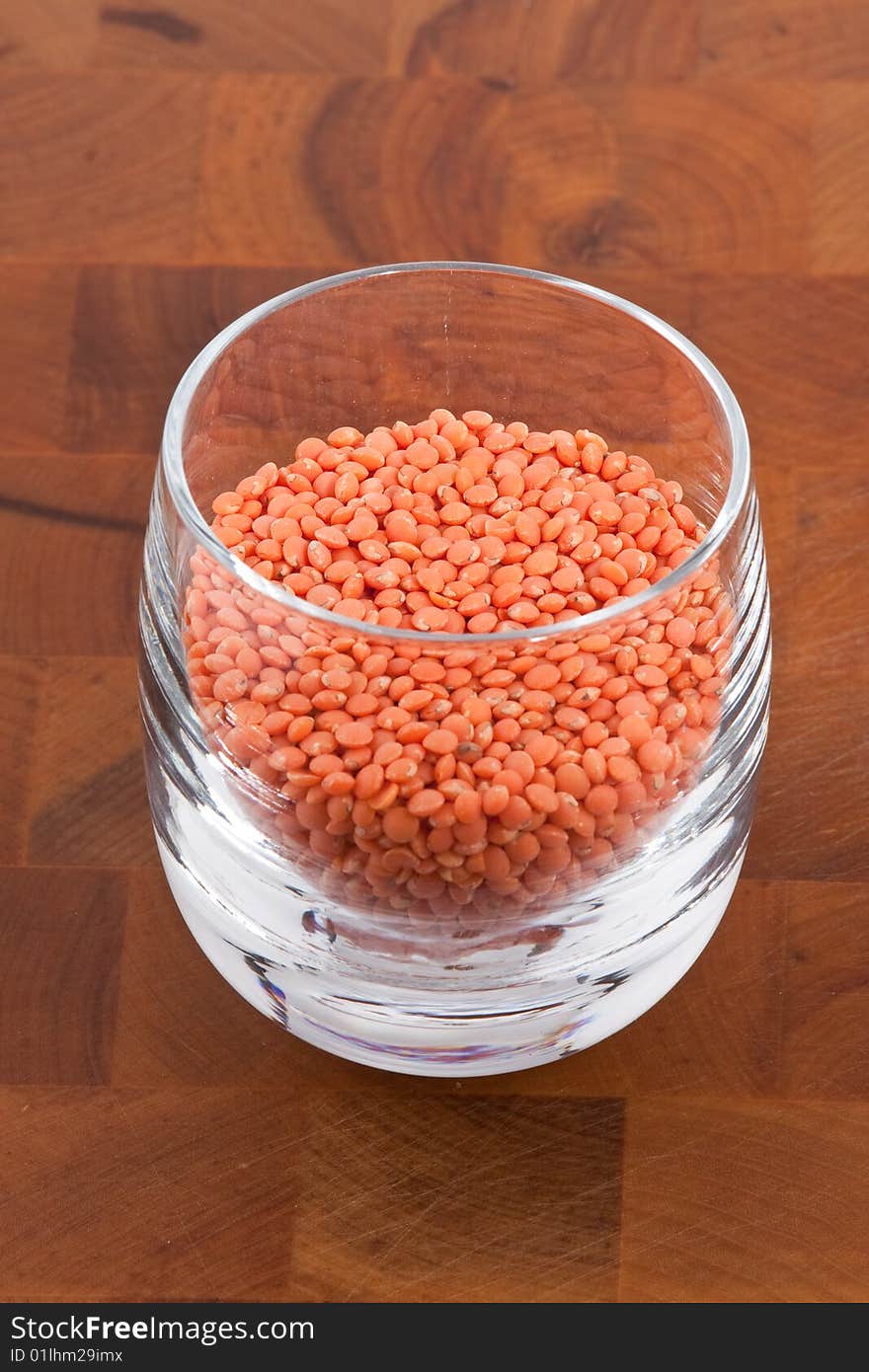 Red lentils in glass on wooden table