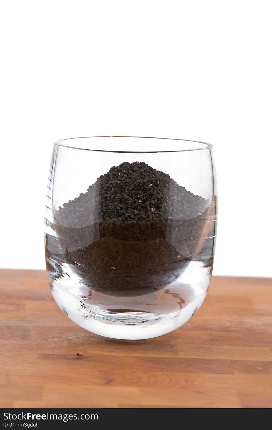 Black Onion Seeds In Glass On Wooden Table