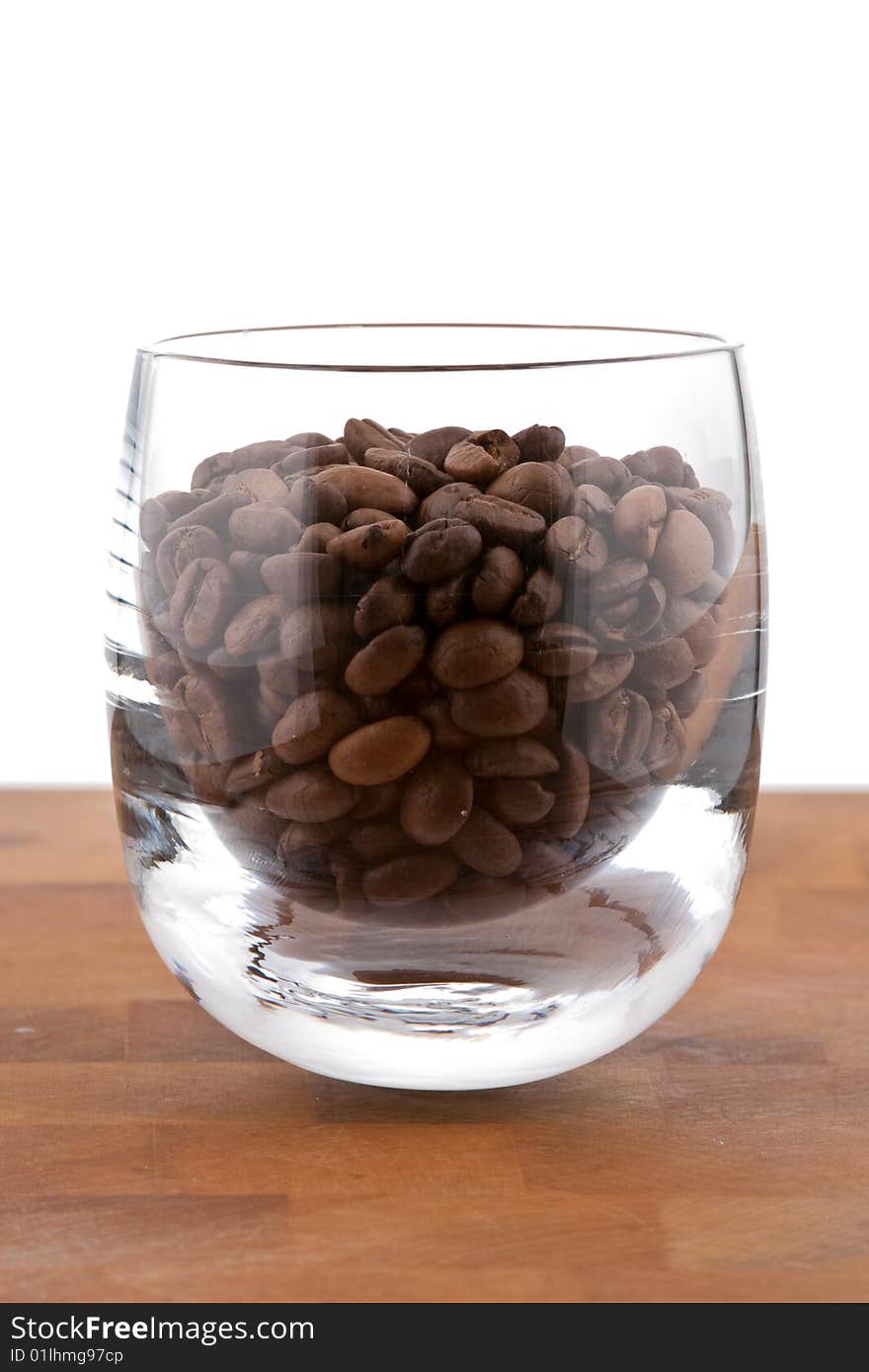 Coffea beans in glass on wooden table, white background