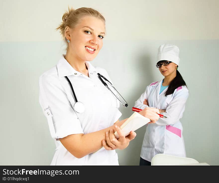 Portrait of a young confident doctor with her assistant in the office. Portrait of a young confident doctor with her assistant in the office