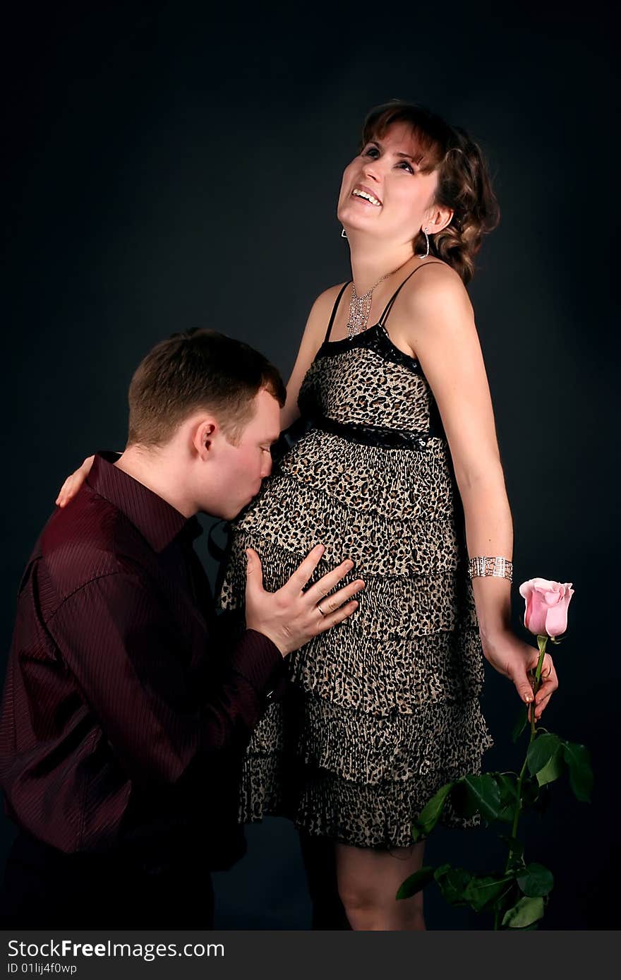 Young beautiful married couple the birth of the second child wait. Dark background. New photos every week