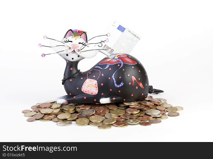 Piggybank (cat) sitting on euro coins with banknote on back