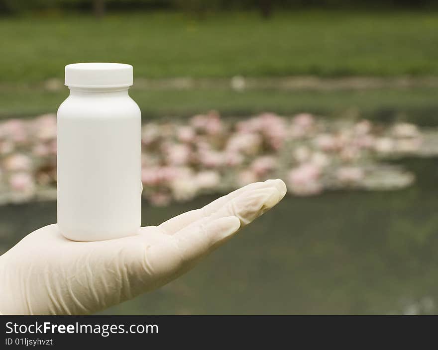 A white box on hand. The white surface waiting for your product label. Water lily in the background.