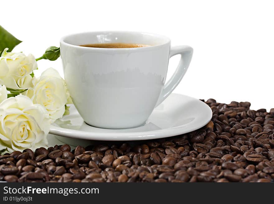 A cup of coffee with white roses and coffee beans isolated on white background. A cup of coffee with white roses and coffee beans isolated on white background