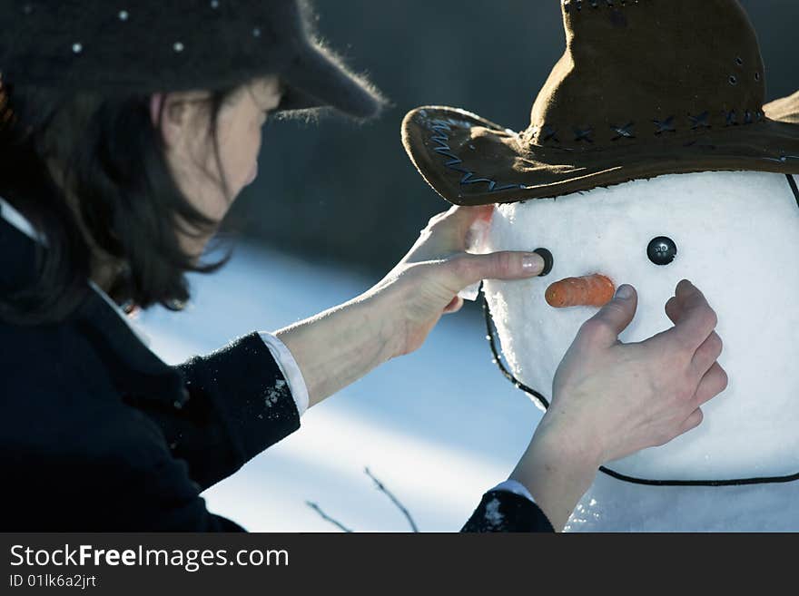 Beautiful woman decorating a snowman