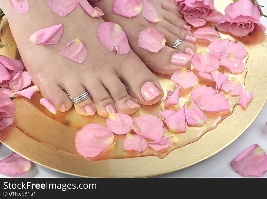 Beautiful woman s  feet with rose petals