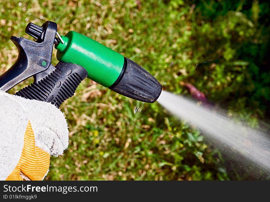 A man's hand keeping a spouting sprinkler at the garden. A man's hand keeping a spouting sprinkler at the garden.