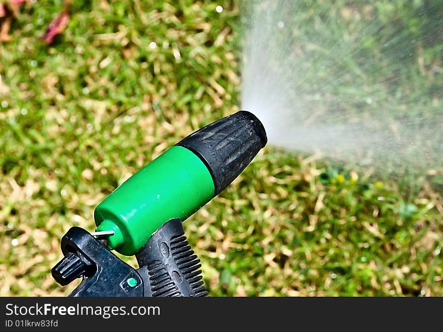 Spouting sprinkler against the green grass background