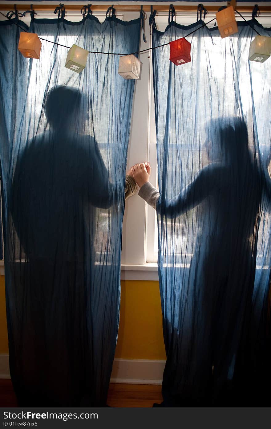 Young couple holding hands behind blue curtains. Young couple holding hands behind blue curtains.