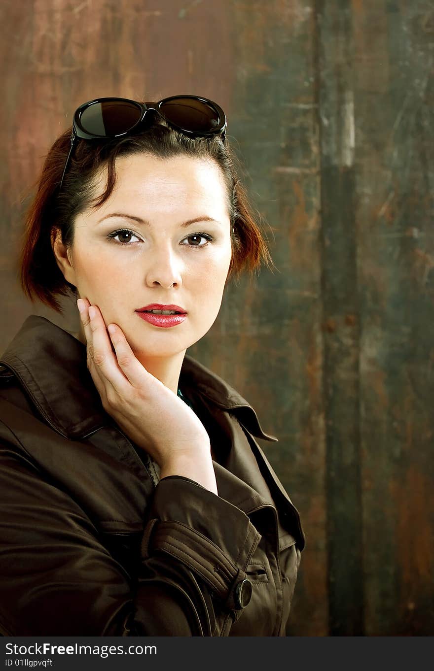 A young stylish woman in a trench coat and sunglasses. A young stylish woman in a trench coat and sunglasses.