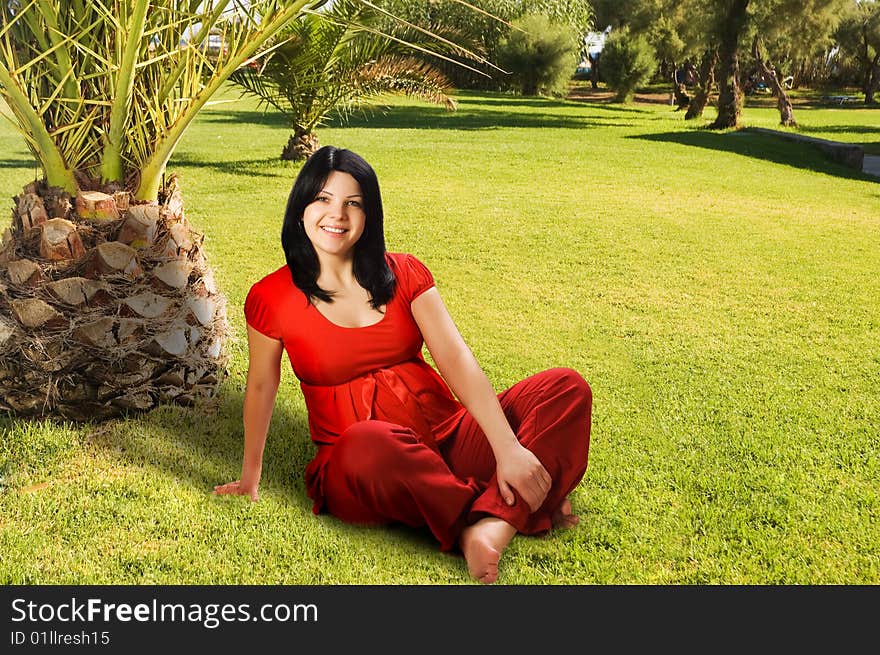 Young Pregnant woman sitting on the grass