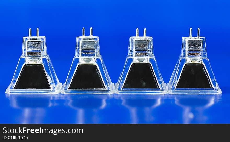 Four atypical square halogen light bulbs standing in a row and isolated on intensive blue background. Four atypical square halogen light bulbs standing in a row and isolated on intensive blue background