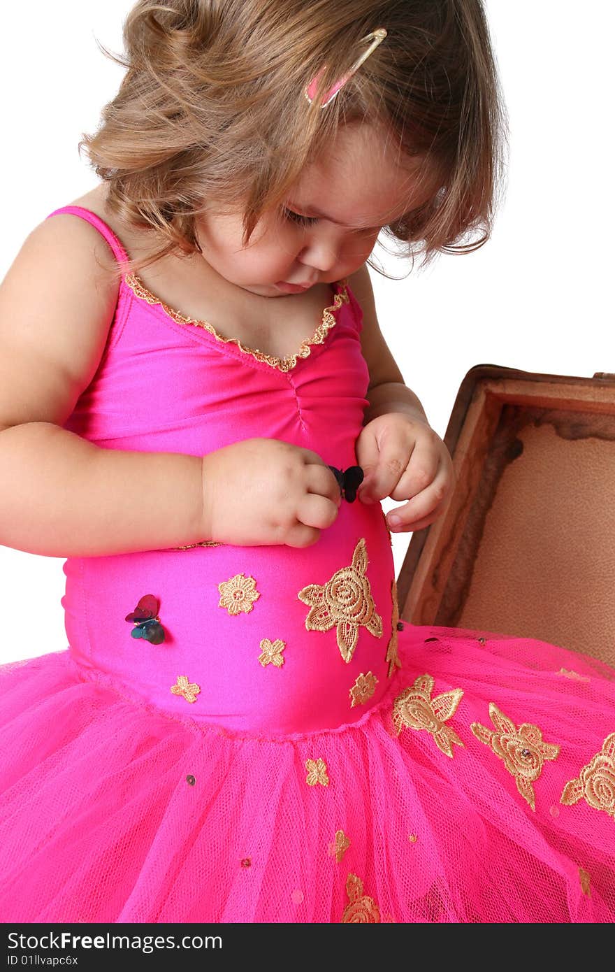 Little girl with wearing a bright pink tutu standing in an old suitcase