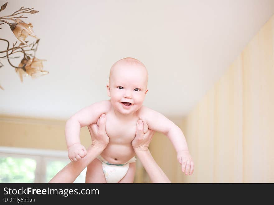 Mother holding enjoying baby in hands at living room