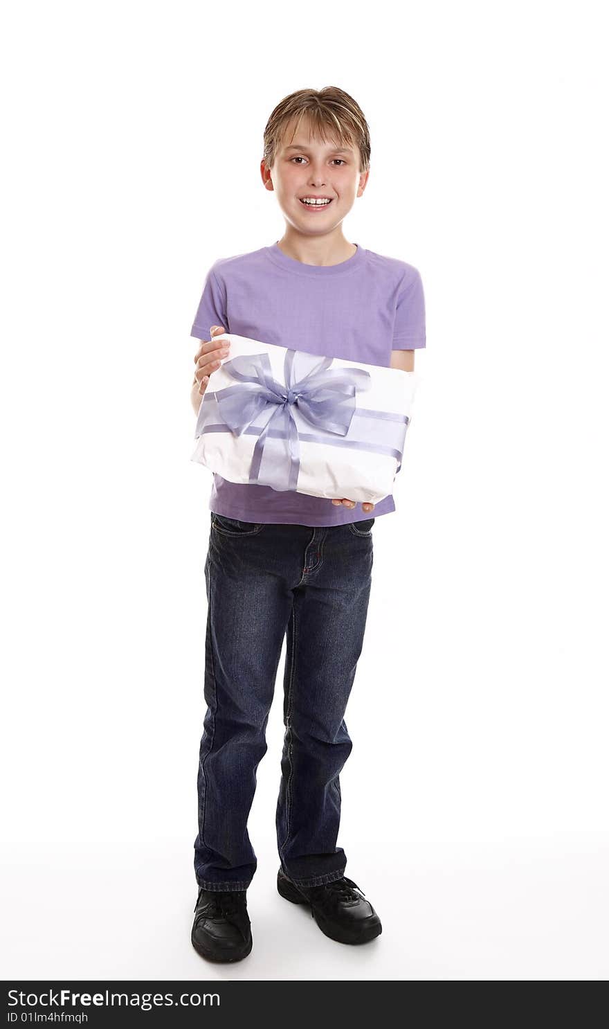 A boy smiles with a wrapped present tied up with big ribbon bow. A boy smiles with a wrapped present tied up with big ribbon bow