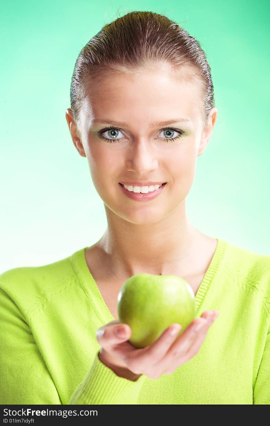 Young beauty woman with apple on green background