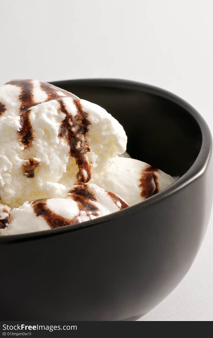 Vanilla ice cream in a bowl with chocolate syrup. Vanilla ice cream in a bowl with chocolate syrup