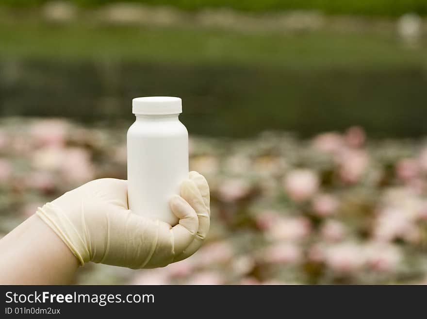 A white box in hand. The white surface waiting for your product label. Water lily in the background.