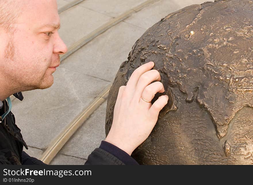 The man searches for the country on the globe of the Earth. The man searches for the country on the globe of the Earth