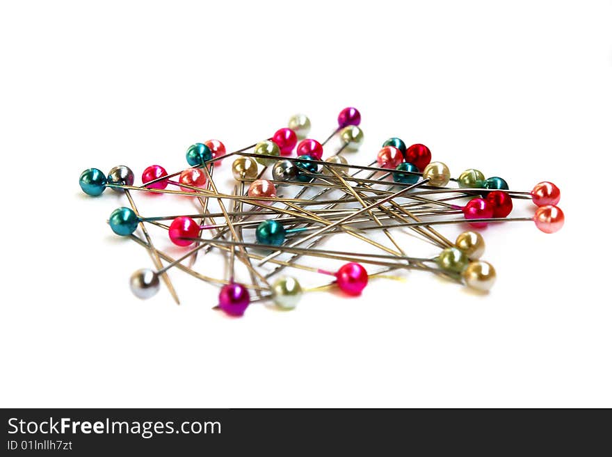 Heap of multi-coloured sewing pins on a white background