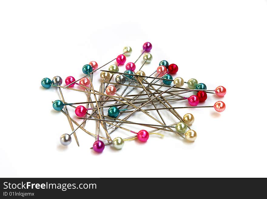 Heap of multi-coloured sewing pins on a white background