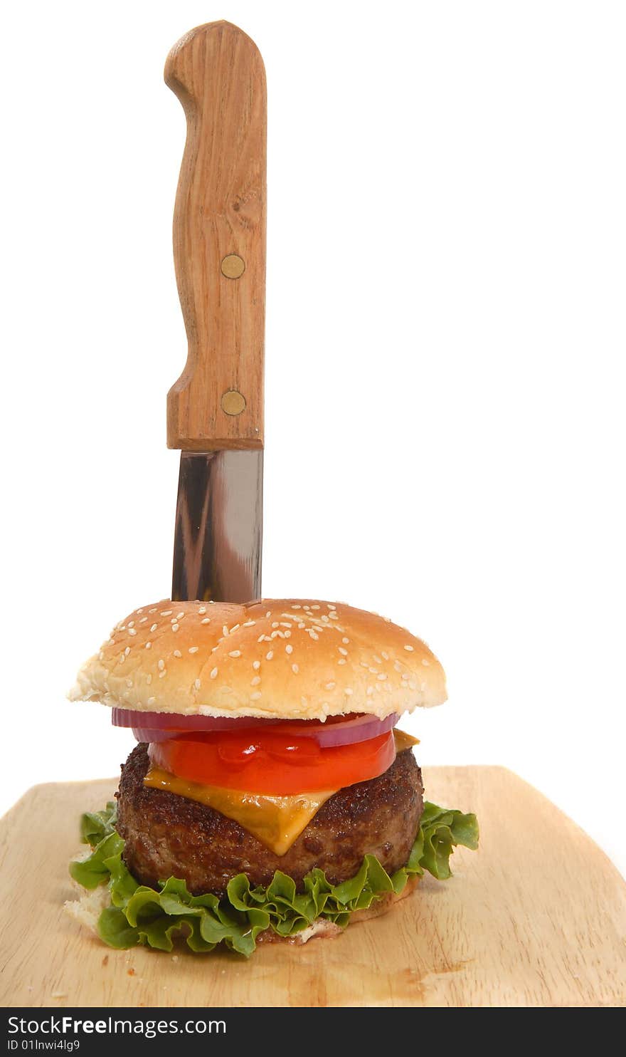 Freshly grilled cheeseburger with a knife running through it. Freshly grilled cheeseburger with a knife running through it