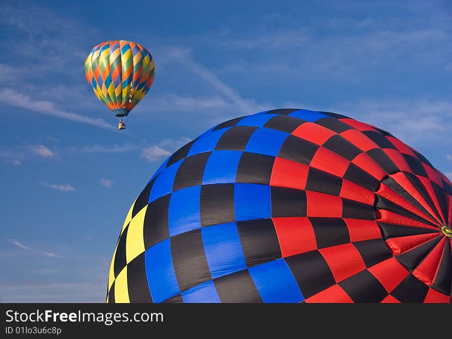 Two hot air balloons with a blue sky background