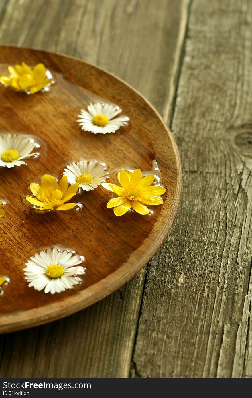 Bowl of water with flowers on wooden