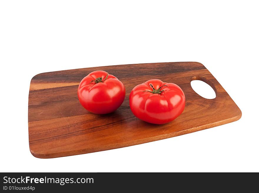 Two tomatoes on cutting board. Isolated on white.