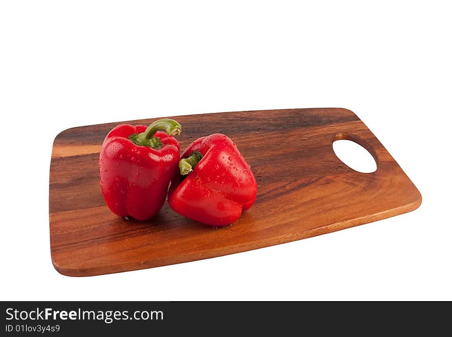 Two wet and red peppers on brown cutting board. Isolated on white. Two wet and red peppers on brown cutting board. Isolated on white.