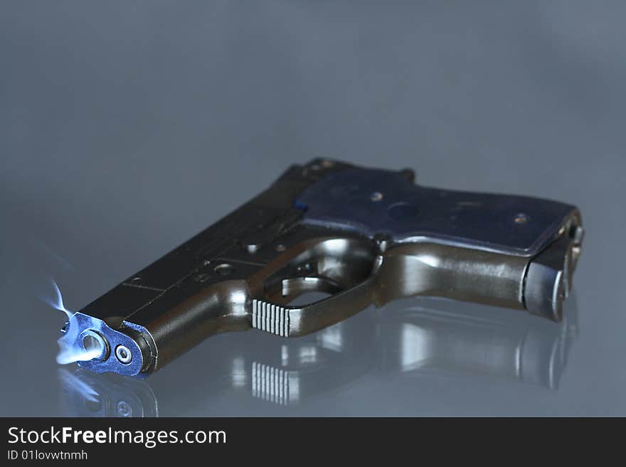 Black automatic pistol with smoke near barrel's hole lying on dark background. Black automatic pistol with smoke near barrel's hole lying on dark background