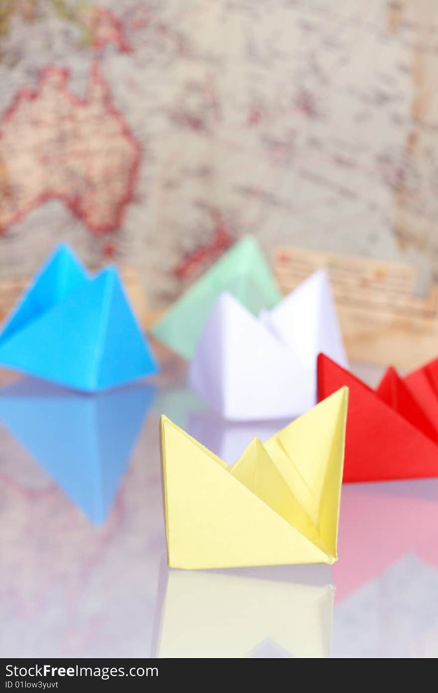 Colourful paper boats on background with old map