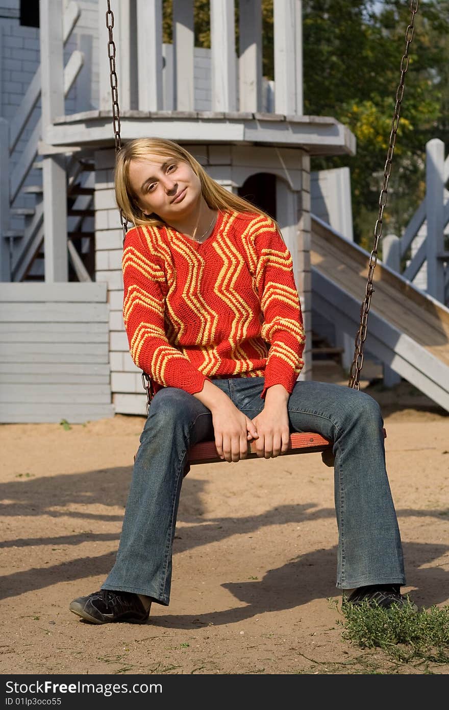 Girl in red pullover sitting on swing