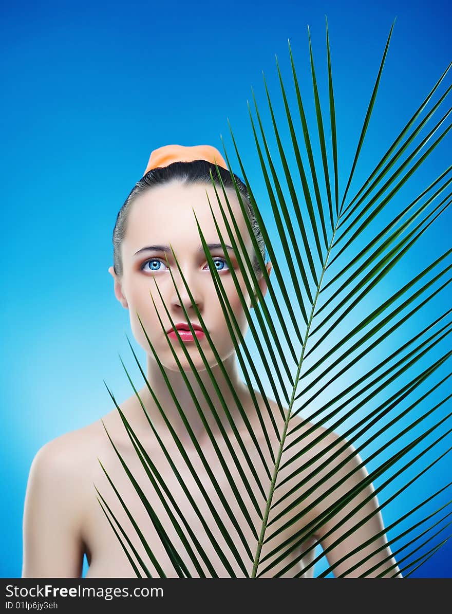 Portrait of beautiful woman with the plant by the sheet of palm. Expressive view of beautiful eyes. Portrait of beautiful woman with the plant by the sheet of palm. Expressive view of beautiful eyes.