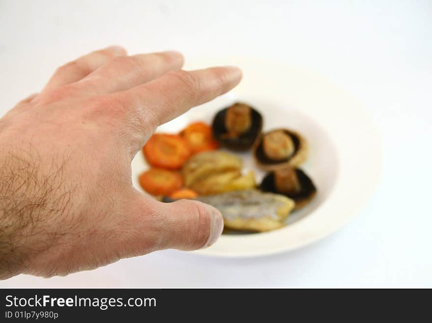 A hand reaching for a far plate with food. A hand reaching for a far plate with food