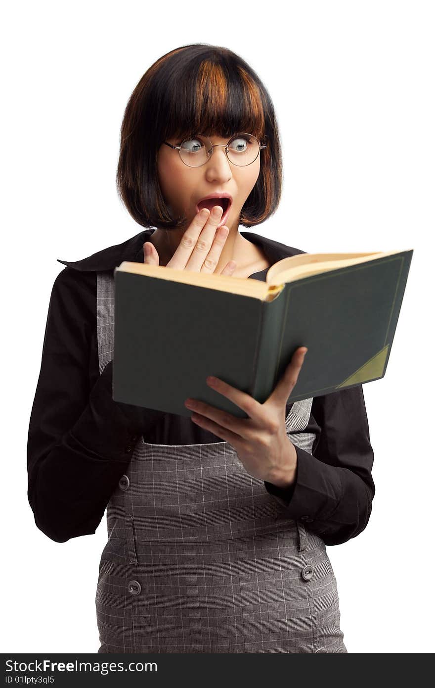 Surprised brunette schoolgirl looking in the book holding in her hands over white background