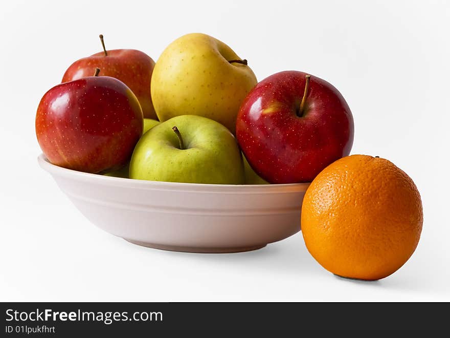 Apples on a plate and an orange against white background, isolated