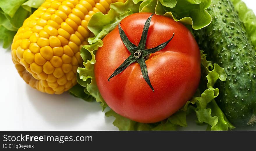 Vegetables on light background: tomatoes, cucumbers, corn on the leaves of lettuce. Vegetables on light background: tomatoes, cucumbers, corn on the leaves of lettuce.