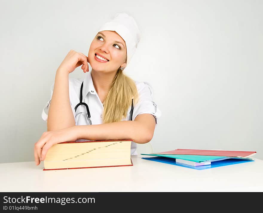 Portrait of a young beautiful thoughtful doctor sitting by the table in her office. Portrait of a young beautiful thoughtful doctor sitting by the table in her office